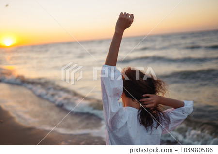 Stylish woman in elegant white dress posing near the sea. People, freedom, lifestyle, travel. 103980586
