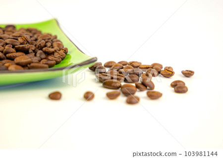 Coffee beans on a green square saucer, white background Coffee beans on a green square saucer, white background 103981144