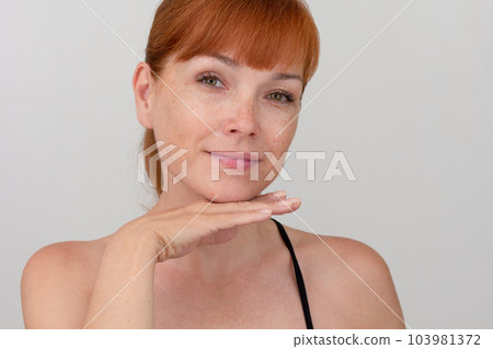 Portrait of cropped caucasian middle aged woman with freckles holding hand under chin on white background looking at camera Portrait of cropped caucasian middle aged woman with freckles holding hand under chin on white background looking at camera 103981372