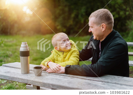 Happy Family: Father And Child Boy Son Playing And Laughing In Autumn Park, Sitting On Wooden Bench And Table. Father And Little Kid Having Fun Outdoors, Playing Together. Father And Son Sitting On A 103981622