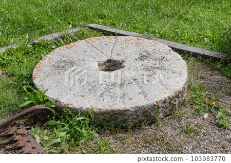Part of an old millstone made of stone Part of an old millstone made of stone 103983770