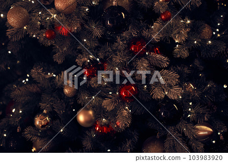 Close-up of a Christmas tree decorated with red and gold balls in the background, illuminated by sparkling and blurred lights in the background with space to copy. High quality photo Close-up of a Christmas tree decorated with red and gold balls in the background, illuminated by sparkling and blurred lights in the background with space to copy. High quality photo 103983920