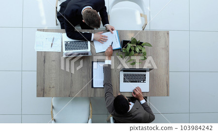 Two successful smiling businessmen are working on a laptop. view from above Two successful smiling businessmen are working on a laptop. view from above 103984242