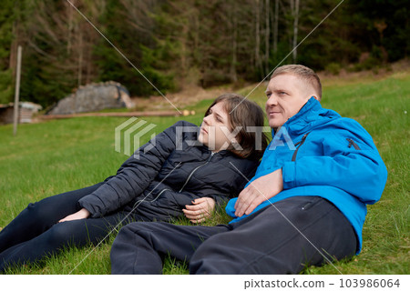 Father laying on his back in the grass with her young daughter. Parenthood and childhood family concept outdoors in nature. happy father and little girl on the grass. Devoted father and daughter lying Father laying on his back in the grass with her young daughter. Parenthood and childhood family concept outdoors in nature. happy father and little girl on the grass. Devoted father and daughter lying 103986064