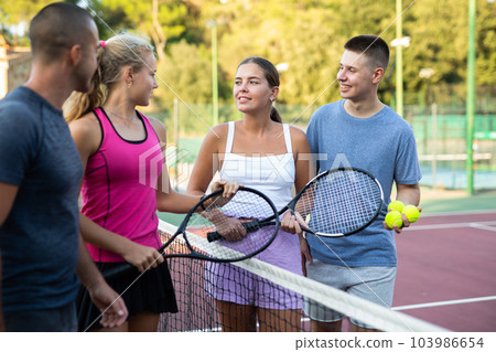 Group of four tennis players standing on court and talking friendly 103986654