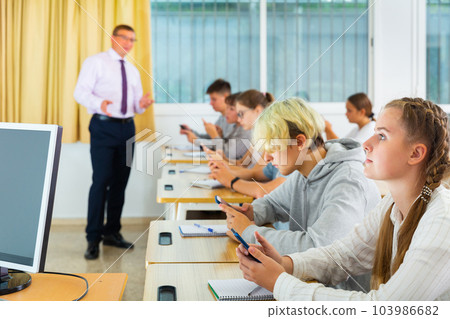 Teenage students using smartphones during lesson Teenage students using smartphones during lesson 103986682