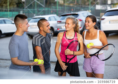 Two pairs of tennis players are happily discussing the past game in car park Two pairs of tennis players are happily discussing the past game in car park 103986719