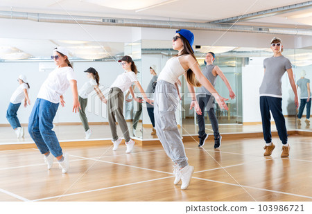 Happy smiling teenagers practicing vigorous hip hop movements in class Happy smiling teenagers practicing vigorous hip hop movements in class 103986721