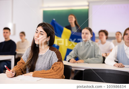 Teacher stands behind students with flag of Sweden 103986834