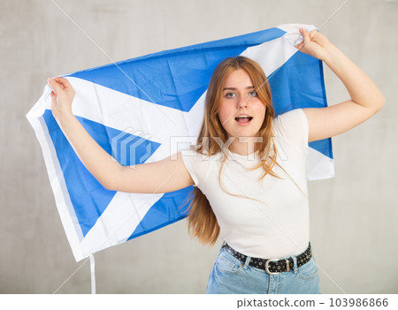 smiling girl in arms raised above head holds cloth of national flag of Scotland smiling girl in arms raised above head holds cloth of national flag of Scotland 103986866