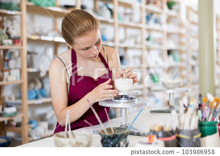 Teenage girl makes ceramic cup in ceramic workshop Teenage girl makes ceramic cup in ceramic workshop 103986958