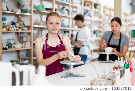 Teenage girl painting ceramic cup in ceramic workshop Teenage girl painting ceramic cup in ceramic workshop 103987011