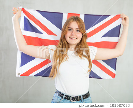 smiling girl in arms raised above head holds canvas of national British flag 103987053
