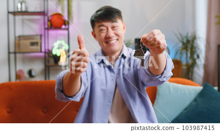 Asian man real estate agent showing the keys of new home house apartment, buying or renting property 103987415