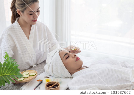 Relaxed young asian woman getting eye nature treatment by cucumber at spa salon. Wellness and healing concept. Relaxed young asian woman getting eye nature treatment by cucumber at spa salon. Wellness and healing concept. 103987662