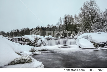 Overcast morning, river in winter, long exposure makes water milky smooth, snow and ice around 103987828