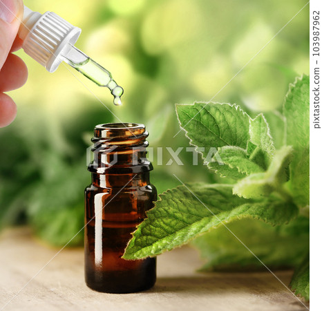Drop of Essential oil of mint falling from glass dropper in brown bottle Drop of Essential oil of mint falling from glass dropper in brown bottle 103987962