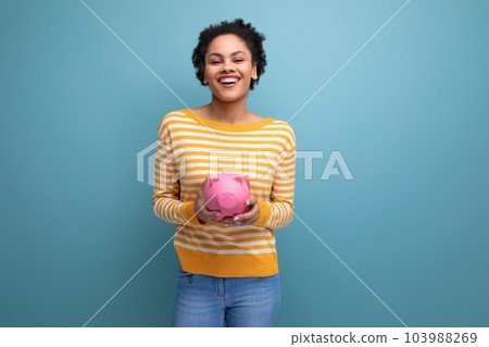 joyful afro brunette 20s latin young woman holding piggy bank of money joyful afro brunette 20s latin young woman holding piggy bank of money 103988269