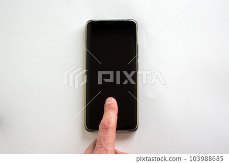 Man's finger unlocks a smartphone on the white background. Copy space for your text. Man's finger unlocks a smartphone on the white background. Copy space for your text. 103988685