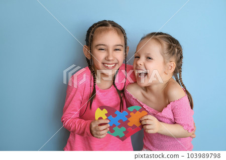 Laughing loudly funny happy girls are holding card a symbol of autism. Care and support of loved ones. 103989798