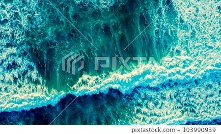 Beautiful  blue ocean waves - aerial view. Top view to the beautiful azure water sea surface.  Atlantic Ocean, Portugal. Drone view of rolling waves with white foam on the summer sunny day. 103990939