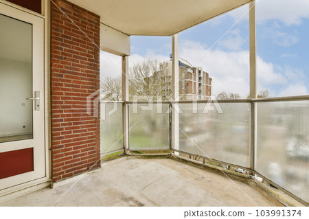 a balcony with brick walls and metal railings, looking out onto the street from one of the two balks a balcony with brick walls and metal railings, looking out onto the street from one of the two balks 103991374