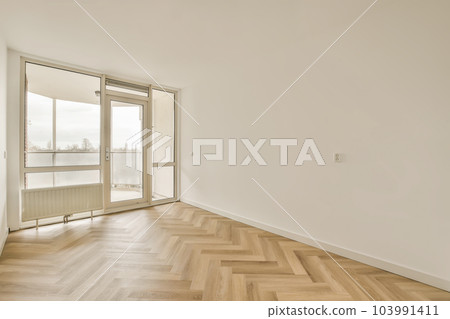 an empty room with wood floors and white walls, looking out onto the street from the living room to the balcony an empty room with wood floors and white walls, looking out onto the street from the living room to the balcony 103991411