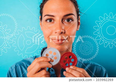 Happy woman joins pieces of gears as concept of partnership and integration Happy woman joins pieces of gears as concept of partnership and integration 103992269