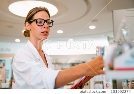 Woman working in the pharmacy looks for the medicine Woman working in the pharmacy looks for the medicine 103992274