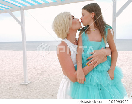 Mother and daughter having tender moment on the beach - Loving mom kissing her child outdoor - Family love concept 103993053
