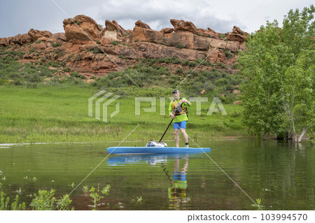 senior male paddler on a touring stand up paddleboard on lake in Colorado foothills - Horsetooth Reservoir near Fort Collins 103994570