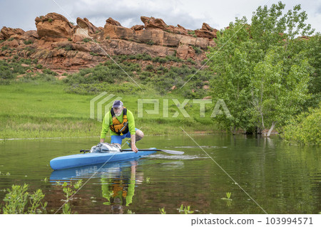 senior male paddler on a touring stand up paddleboard on lake in Colorado foothills - Horsetooth Reservoir near Fort Collins senior male paddler on a touring stand up paddleboard on lake in Colorado foothills - Horsetooth Reservoir near Fort Collins 103994571