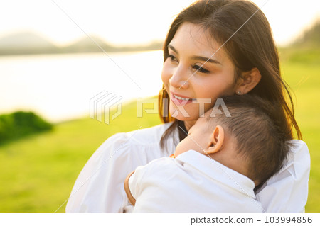 Loving mother holding and carrying her newborn baby at public park 103994856