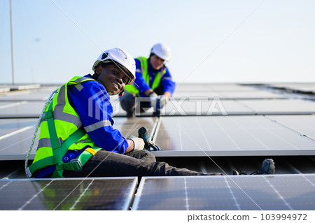 Professional technicians installing solar panels on rooftop of plant Professional technicians installing solar panels on rooftop of plant 103994972