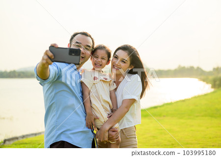 Happy family relaxing and resting in park together on weekend Happy family relaxing and resting in park together on weekend 103995180