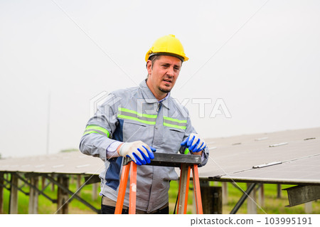 Professional engineer maintaining solar panels on solar cell farm 103995191