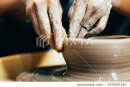 Craftsman potter making jug of clay on the potter's wheel circle in workshop Craftsman potter making jug of clay on the potter's wheel circle in workshop 103995567