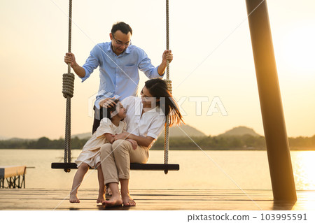 Family enjoying with outdoor activities sitting on swing with sunset 103995591