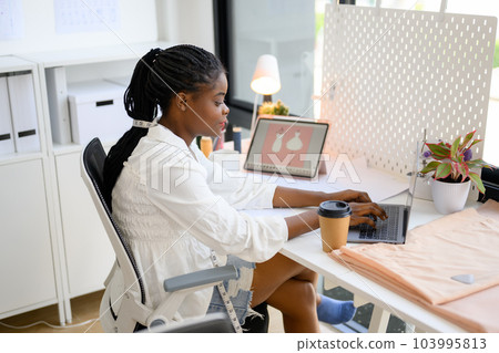 Happy dressmaker designer working in workshop studio Happy dressmaker designer working in workshop studio 103995813