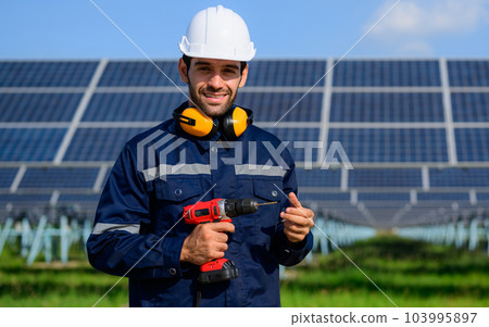 Technician worker installing solar panels at solar cell farm 103995897
