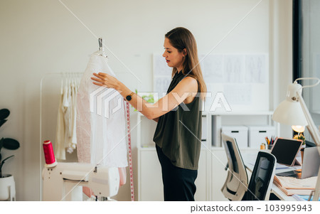 Beautiful woman dressmaker working in workshop studio Beautiful woman dressmaker working in workshop studio 103995943