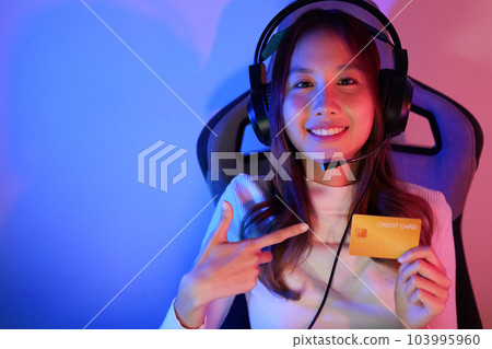 Female gamer make purchase within game, Gamer holding credit card 103995960