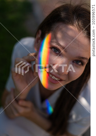 Portrait of caucasian woman with rainbow beam on her face outdoors. Portrait of caucasian woman with rainbow beam on her face outdoors. 103996571