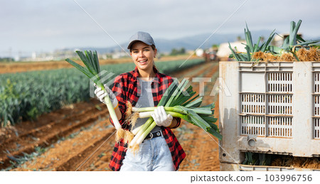 Portrait of positive girl farmer with leek crop 103996756