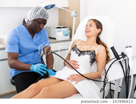 Cosmetologist reducing cellulite on the hips of a female patient Cosmetologist reducing cellulite on the hips of a female patient 103996813