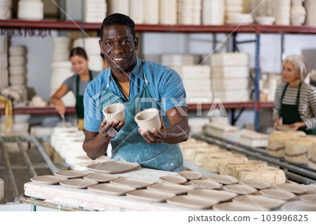 Portrait of african american man displaying cups at workshop 103996825