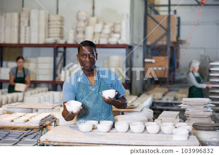 Portrait of african american man displaying cups at workshop 103996832