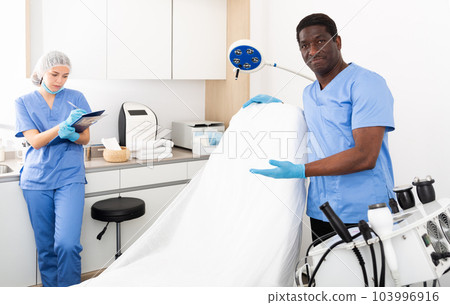 Two professional cosmetologists man and woman welcoming patient Two professional cosmetologists man and woman welcoming patient 103996916