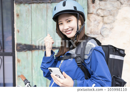 Food delivery image Female delivery person delivering by bicycle Food delivery image Female delivery person delivering by bicycle 103998110