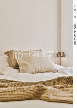 a bed with two pillows and a blanket on the headboard, in front of it is a white wall 103999156